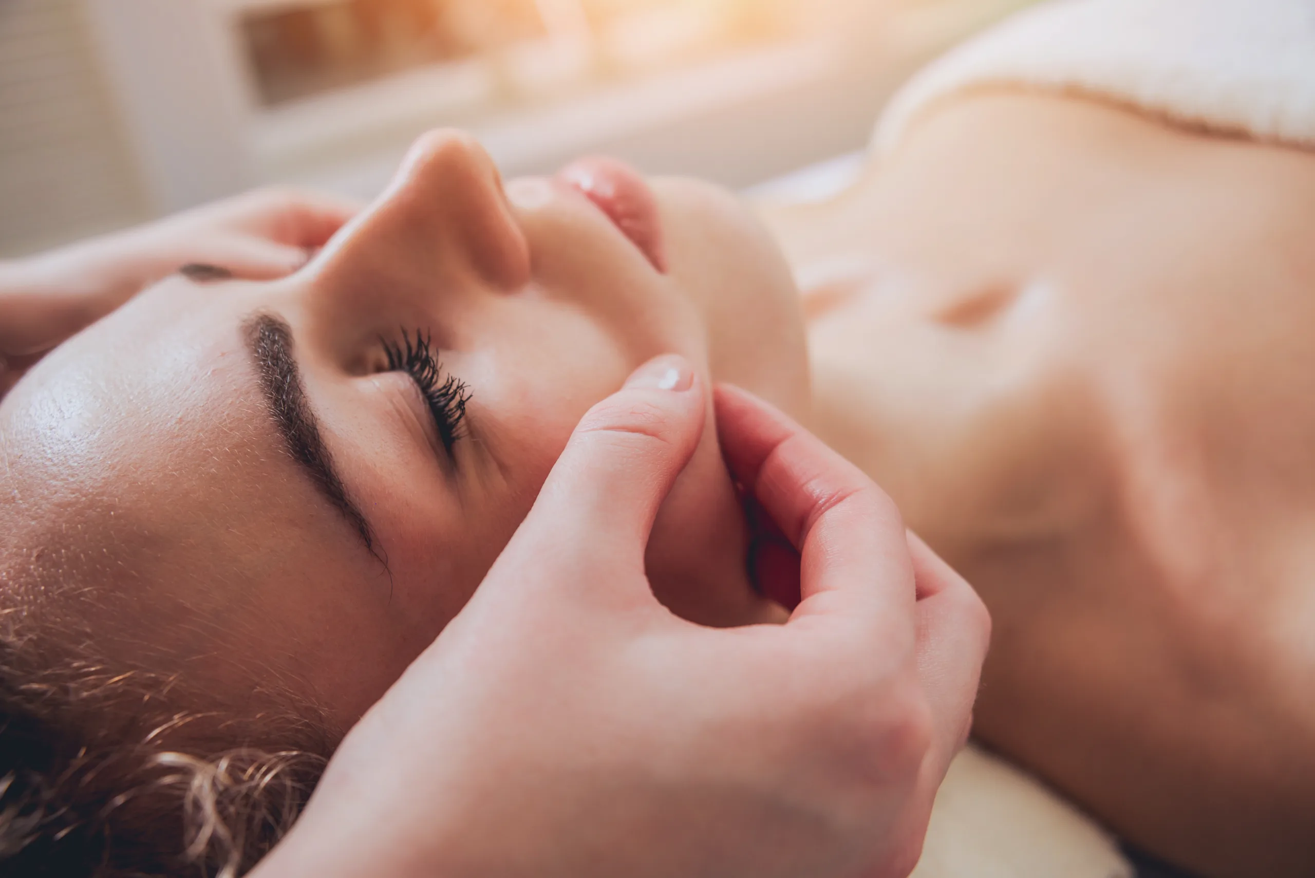 Beautiful woman in spa salon getting facial massage AdobeStock 152357031 1 scaled