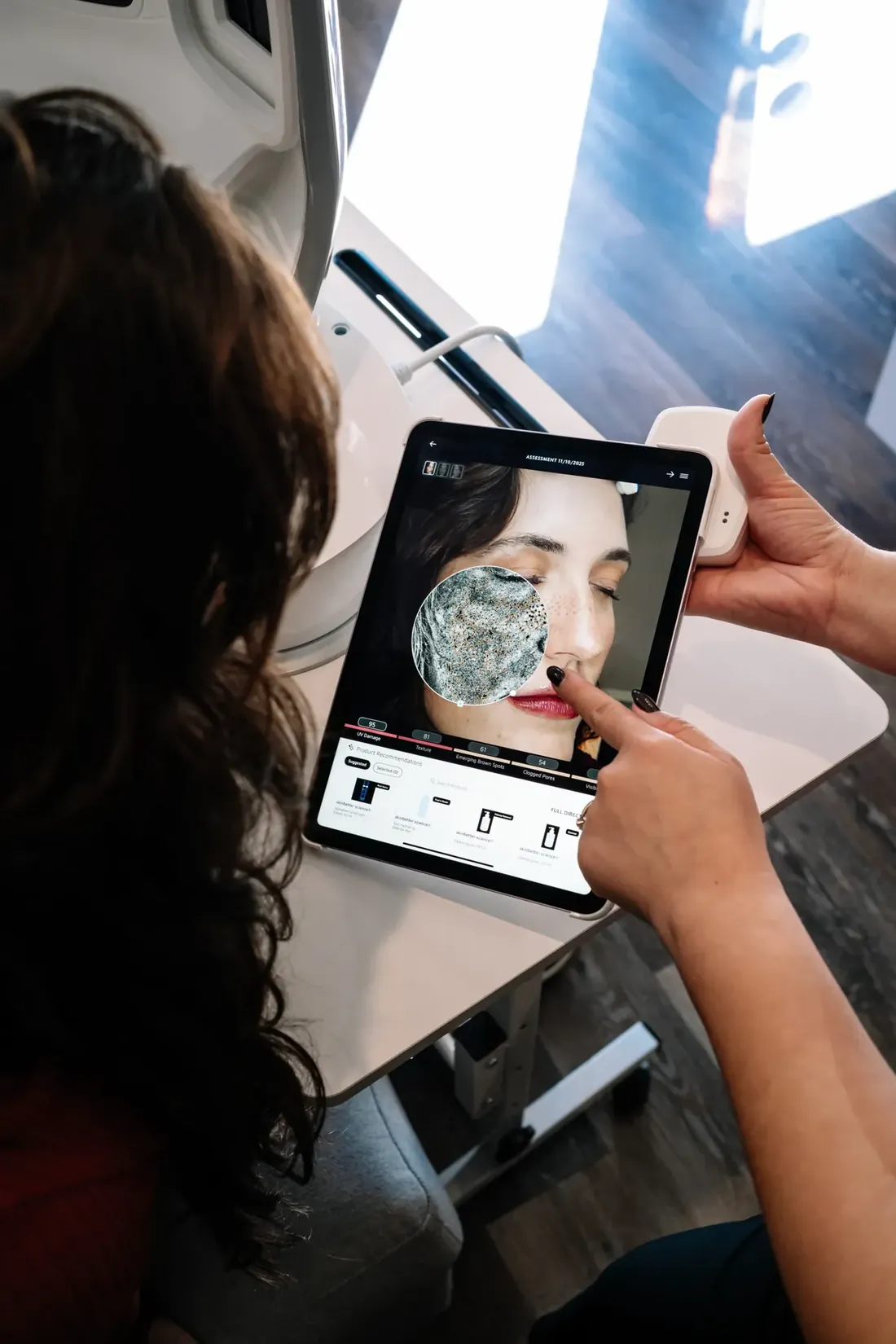 Esthetician reviewing a facial skin analysis scan on a tablet with a client